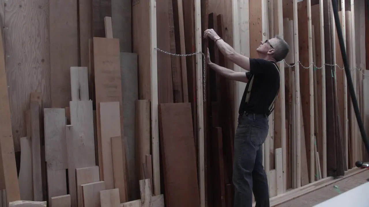 Woodworker selecting rough lumber from storage rack in wood work shop