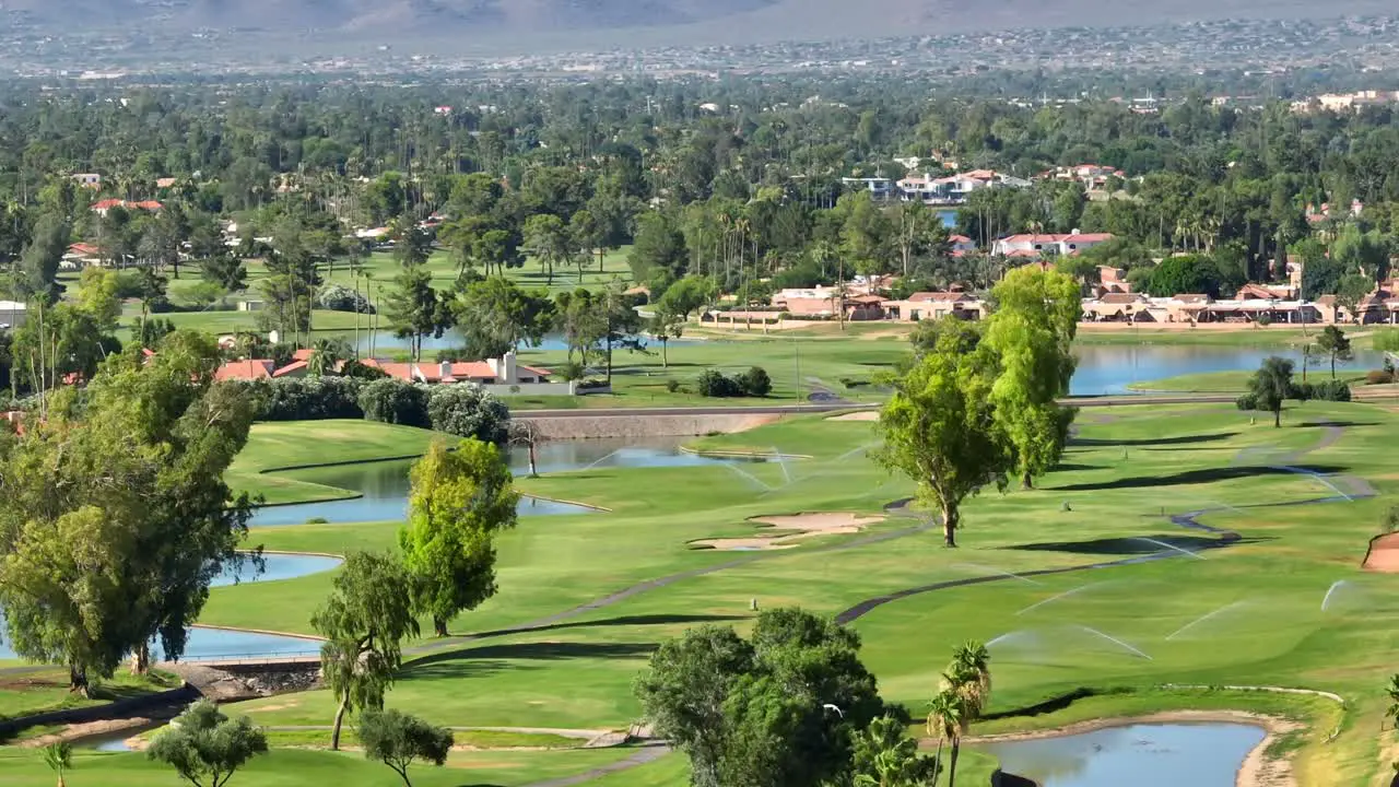 A green golf course in Scottsdale Arizona with lakes and sprinklers