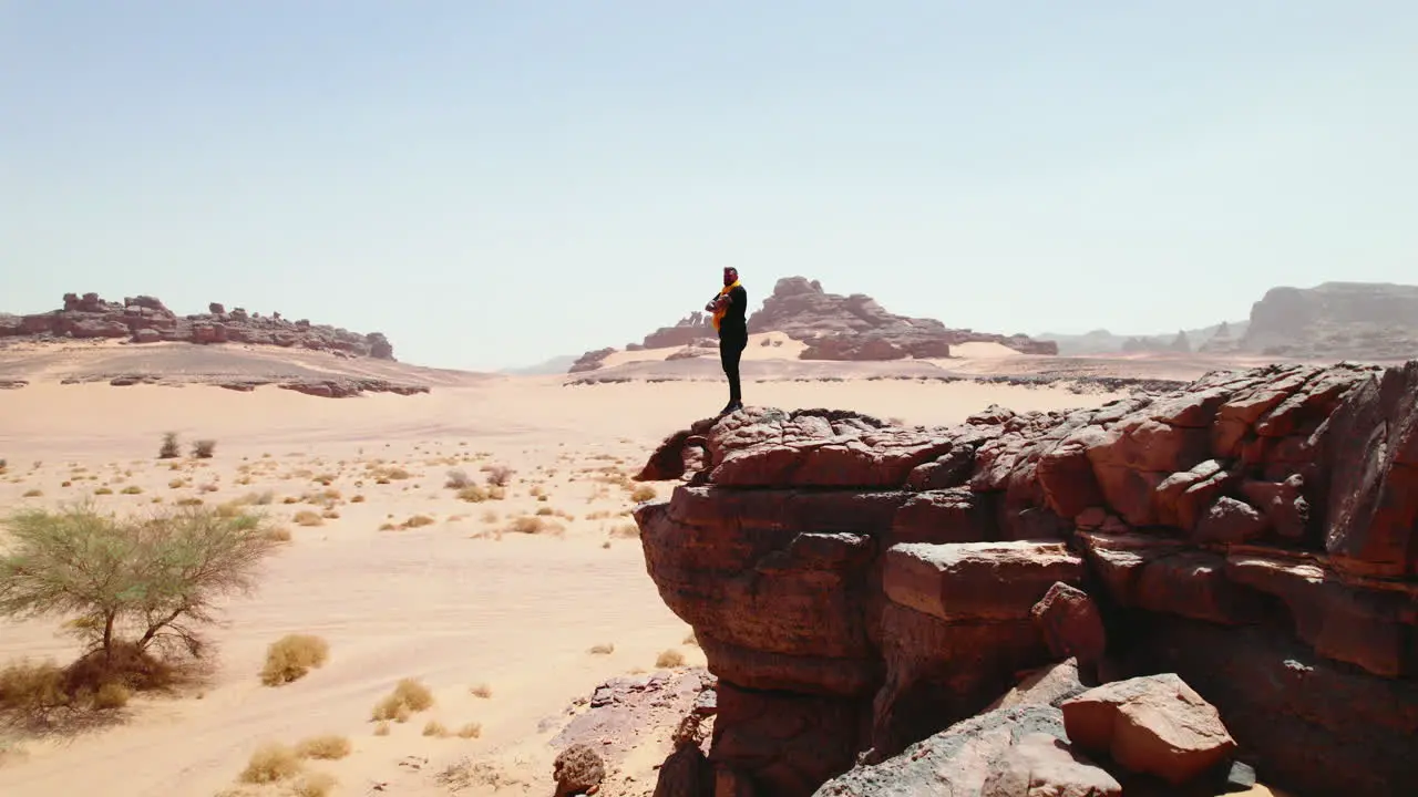 Man Stand On The Edge Of Rock Looking On Vast Landscape Of Desert In Djanet Algeria