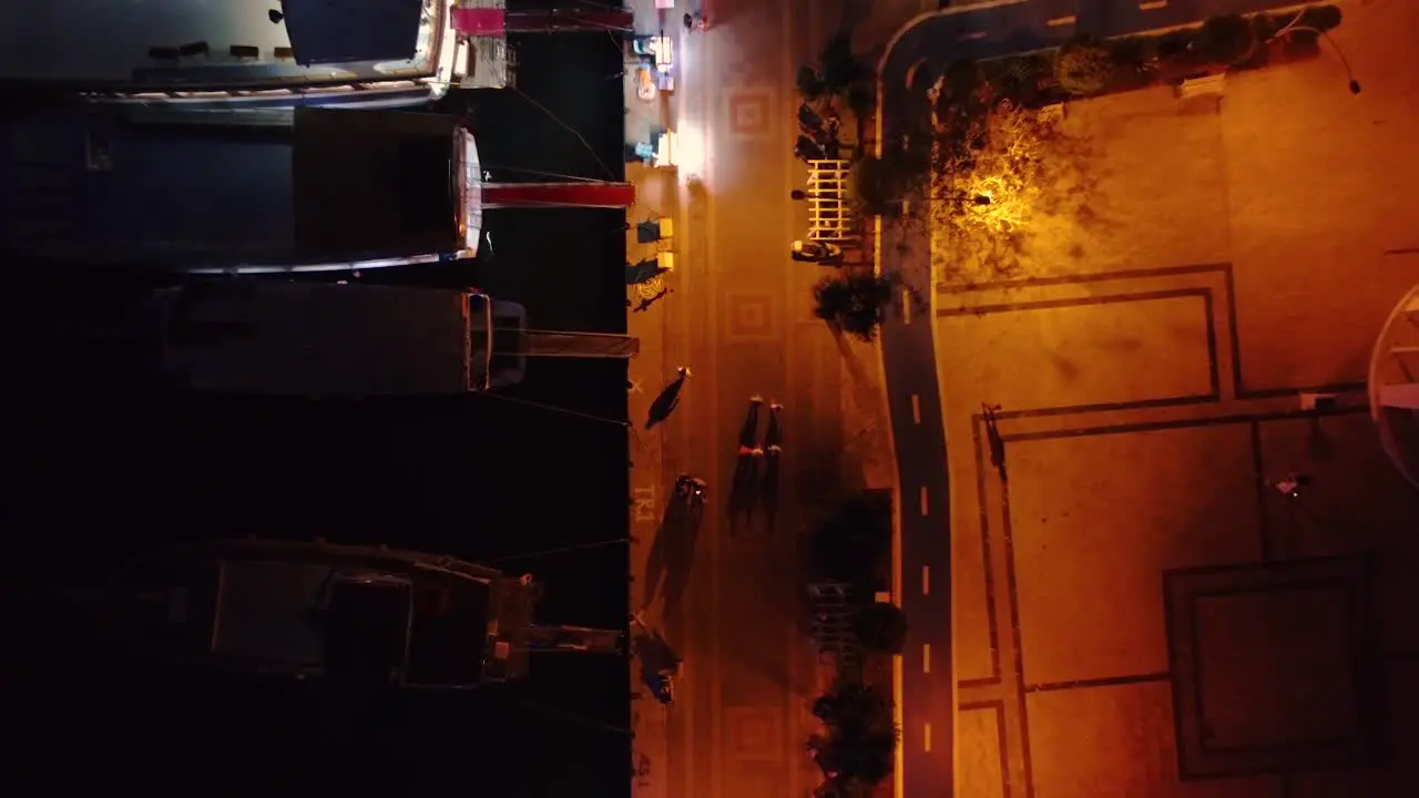 Aerial top down shot of port during night time with boats docked and people walking