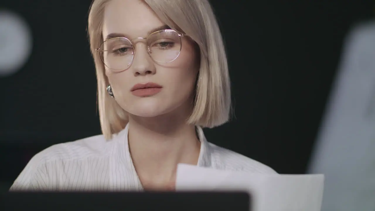 Focused business woman working with documents front laptop in night office