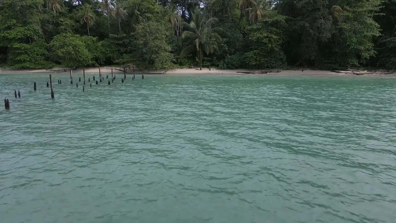 AERIAL Hovering over deep blue water looking onto forested island