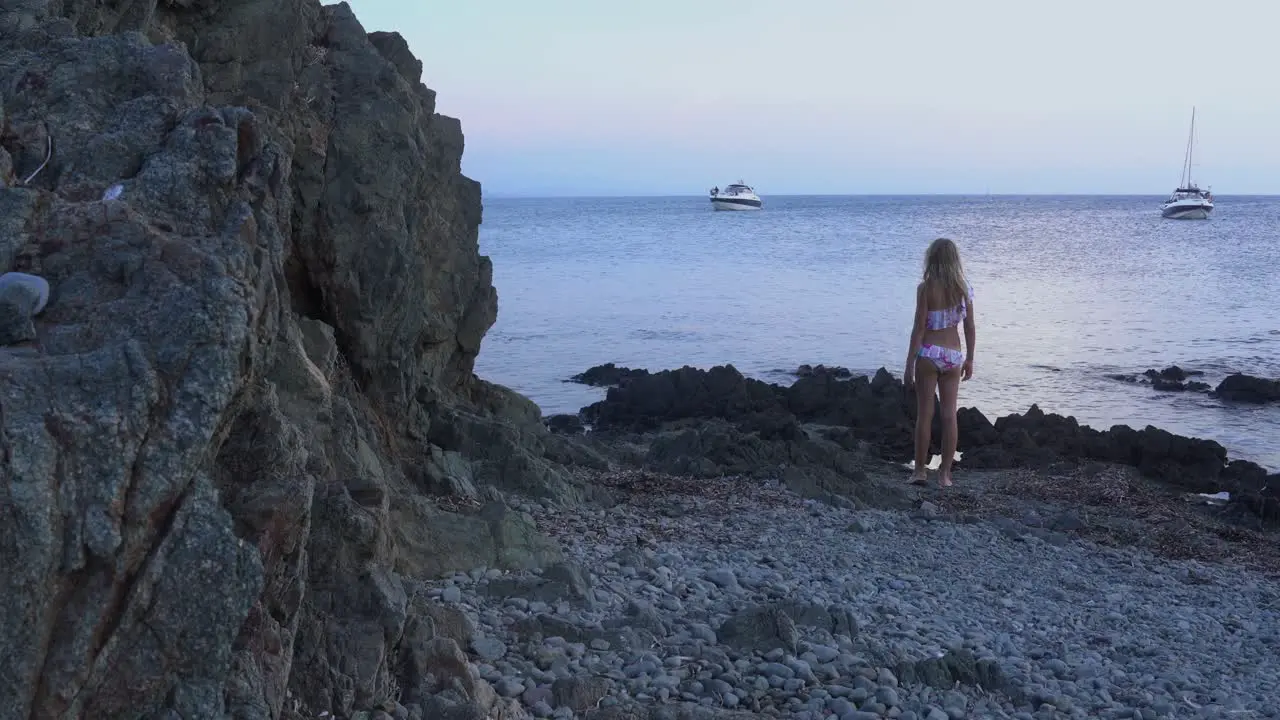 Beautiful girl walks up to the sea and throws a rock into the water and then watches how it sinks