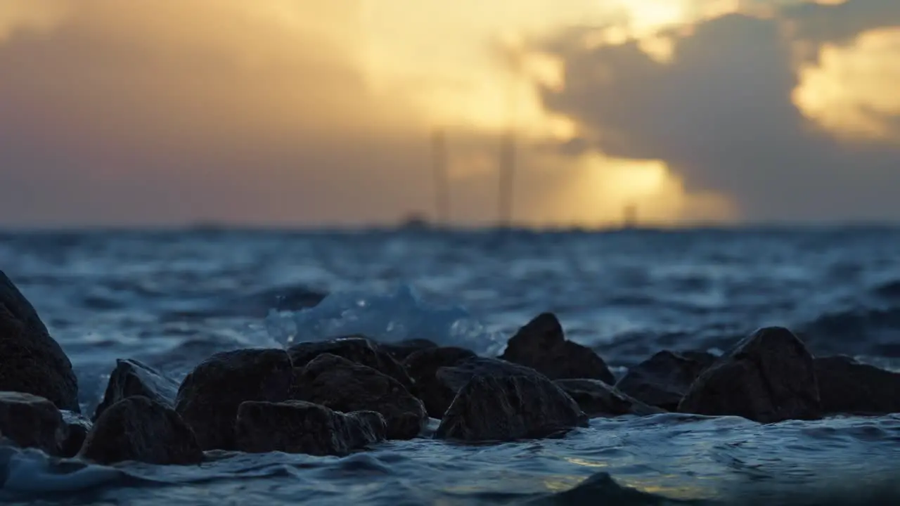 Cinematic slow motion sea water hitting the rocks in the beautiful sunset