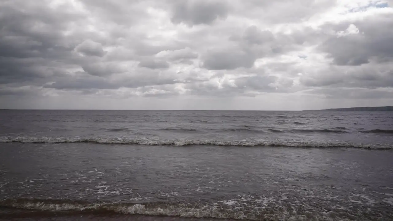 A dramatic skyline over the sea from the shoreline waves lap at the shore