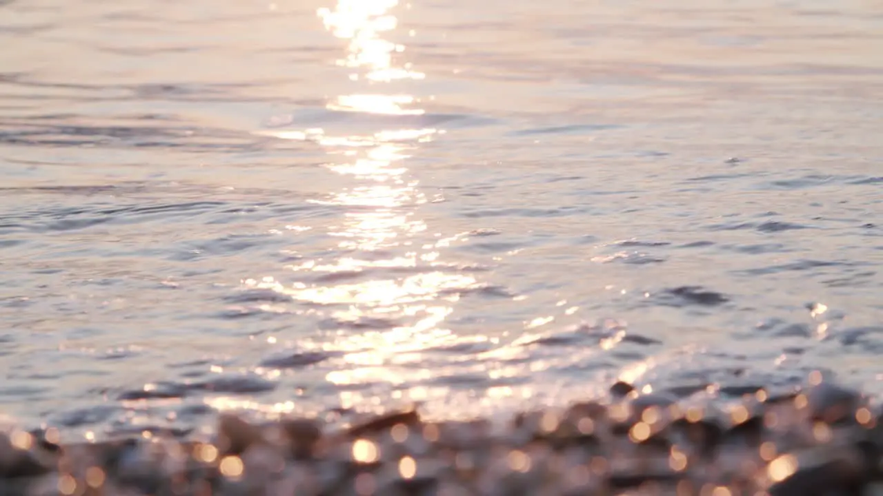 Close up calm waves ripple on sand defocused pebbles foreground Almeria Spain