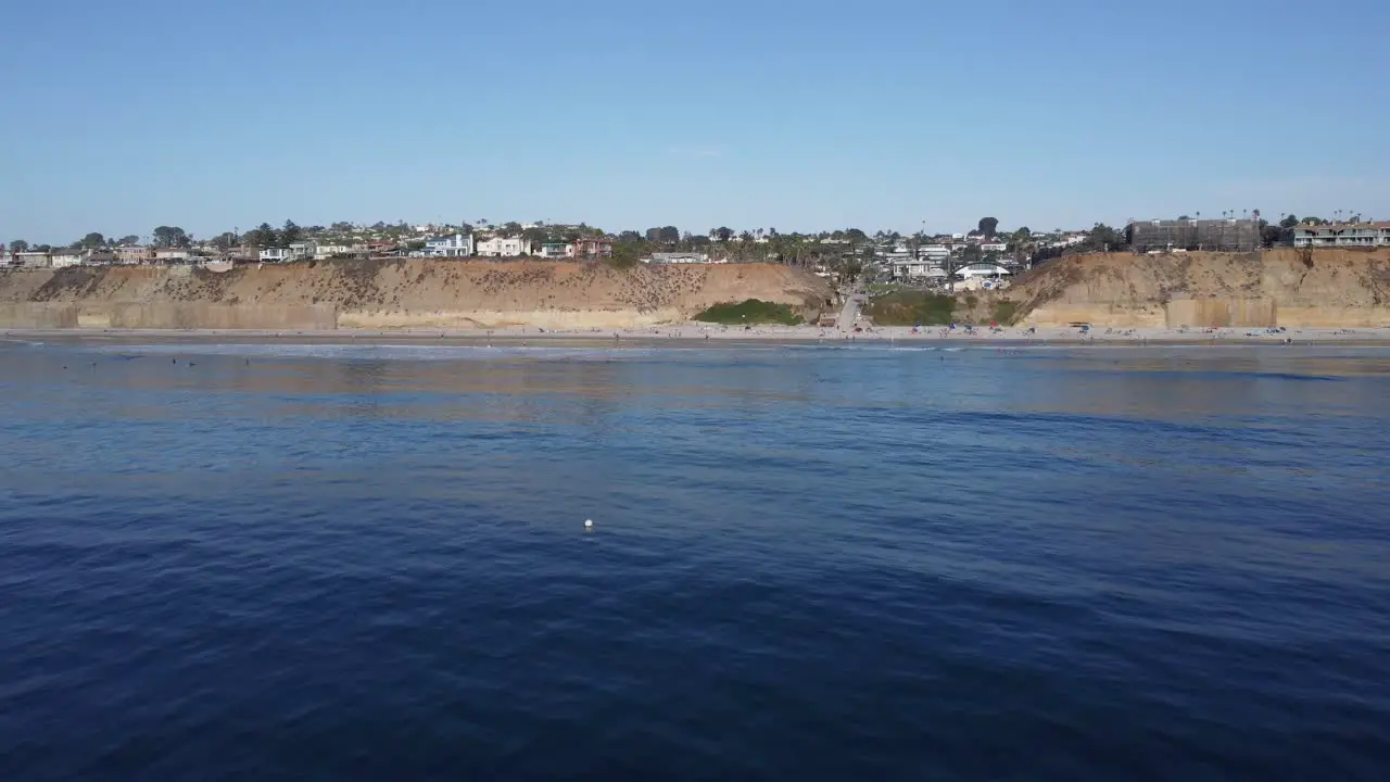 A stunning aerial drone reveal shot flying over water revealing the coast Solana Beach San Diego California