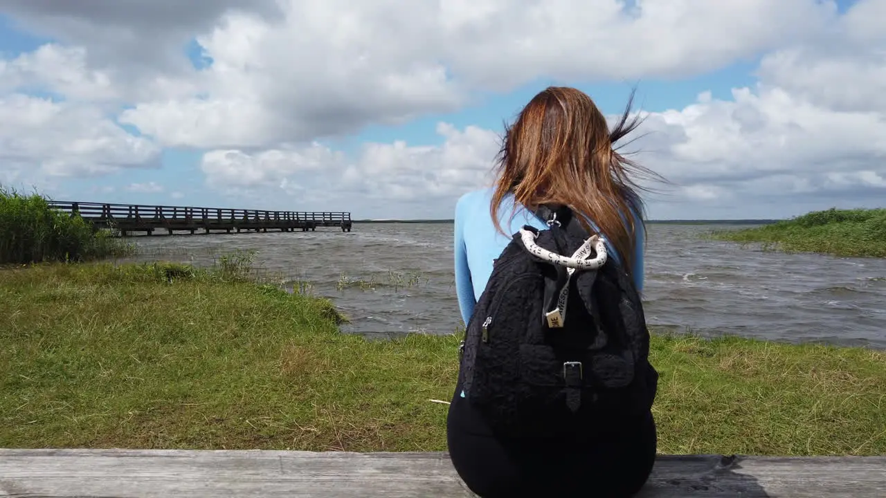 Cinematic shot of a woman sitting on a log and admiring the lagoon