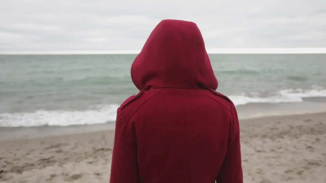 A Person Wearing A Red Hoodie Jacket Watching The Ocean Waves Close Up Shot