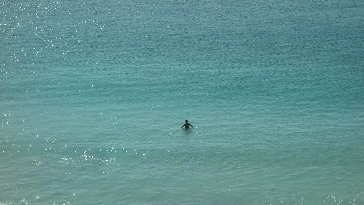 Man swimming lonely in clear shallow sea water at sunny morning