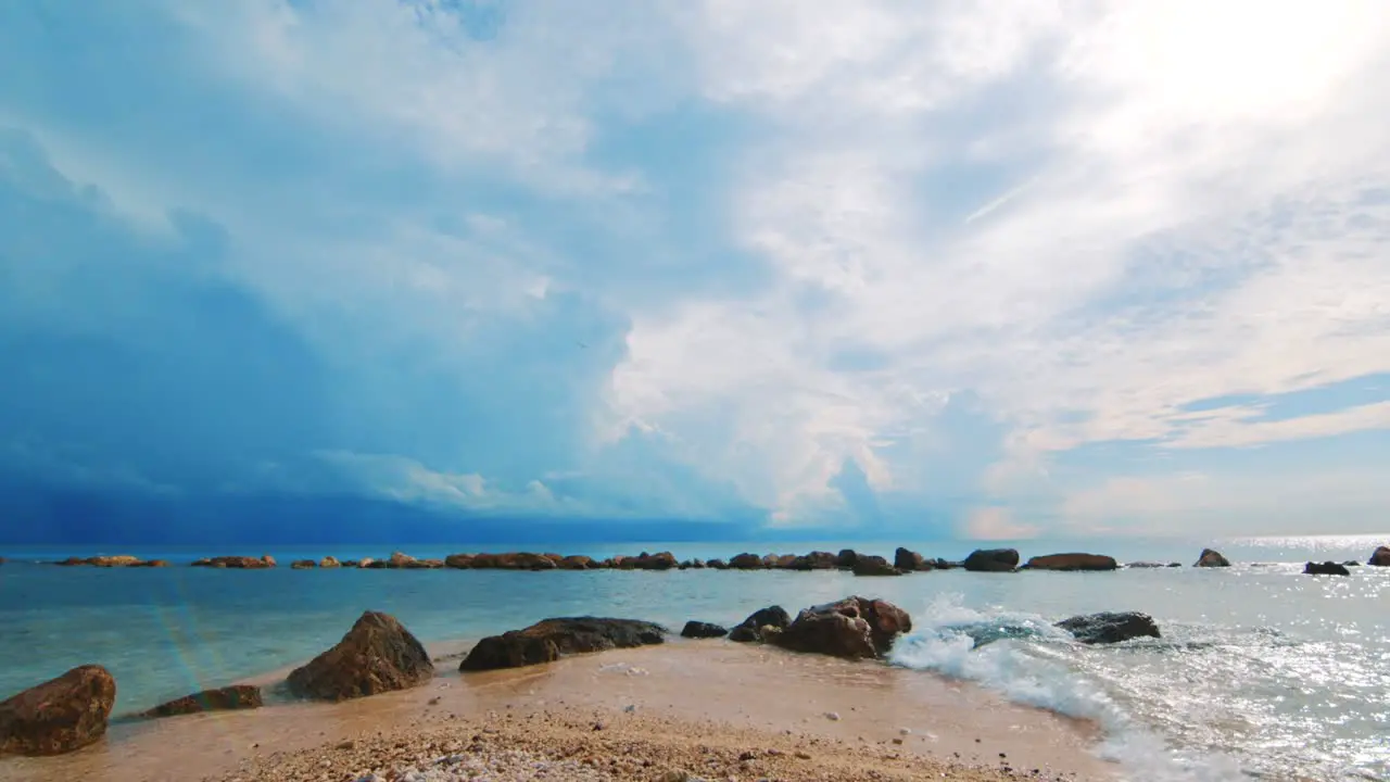 Slowmo gentle waves breaking on sandy Caribbean beach with storm clouds behind