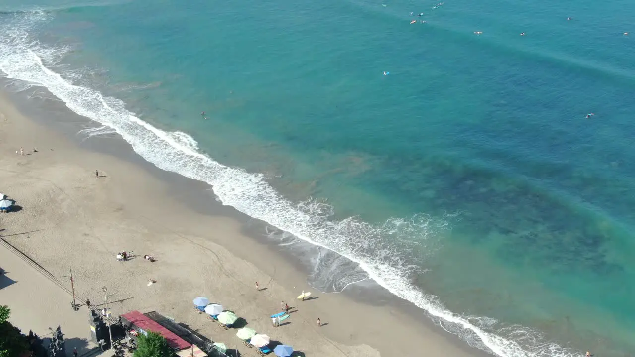 The hotels with numerous Stand Patio Umbrellas employed so that tourists can relax can be seen and on the other side of the rich blue waves of the sea where foamy waves are headed toward the beach