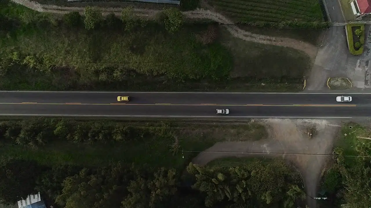 Overhead aerial drone shot the traffic on a lane surrounded by nature in the city outskirts