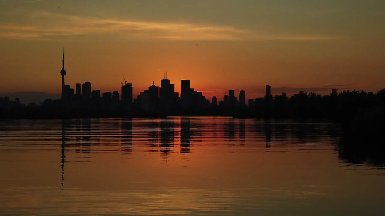 Slow motion magic hour shot of Toronto skyline silhouetted against an orange sky