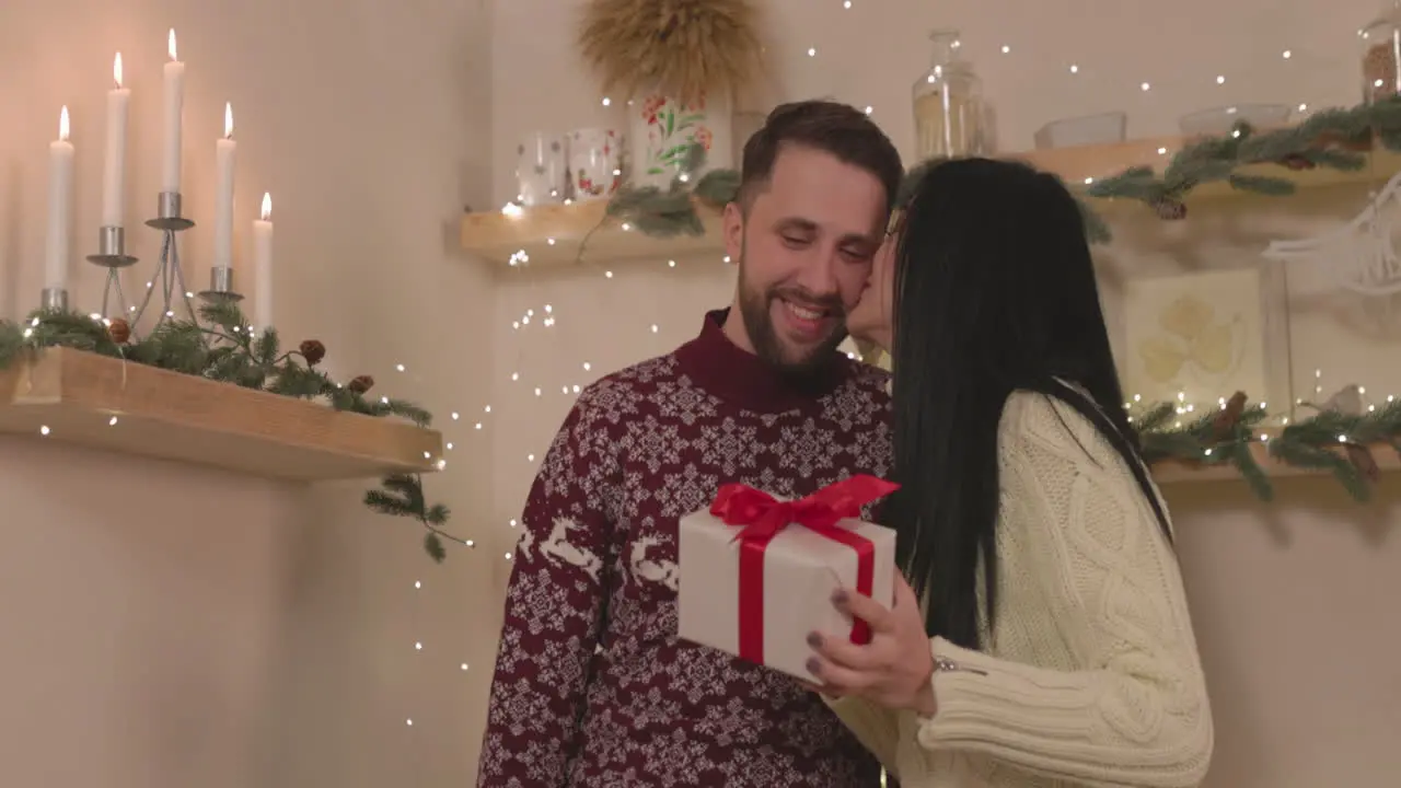 Mujer Feliz Sosteniendo Una Caja De Regalo De Navidad Y Besando A Su Novio En Casa 1