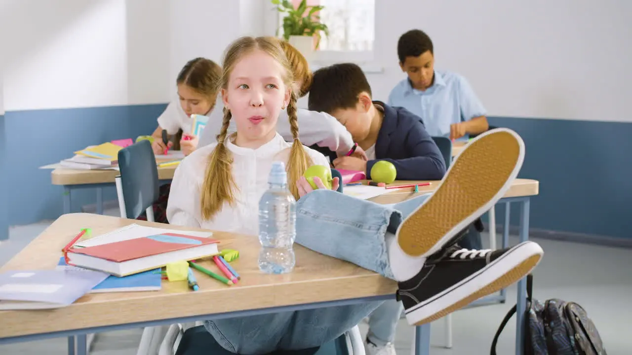 Studentin Die Mit Ihren Beinen Auf Dem Tisch Im Englischen Klassenzimmer Am Schreibtisch Sitzt Während Sie Einen Apfel Isst