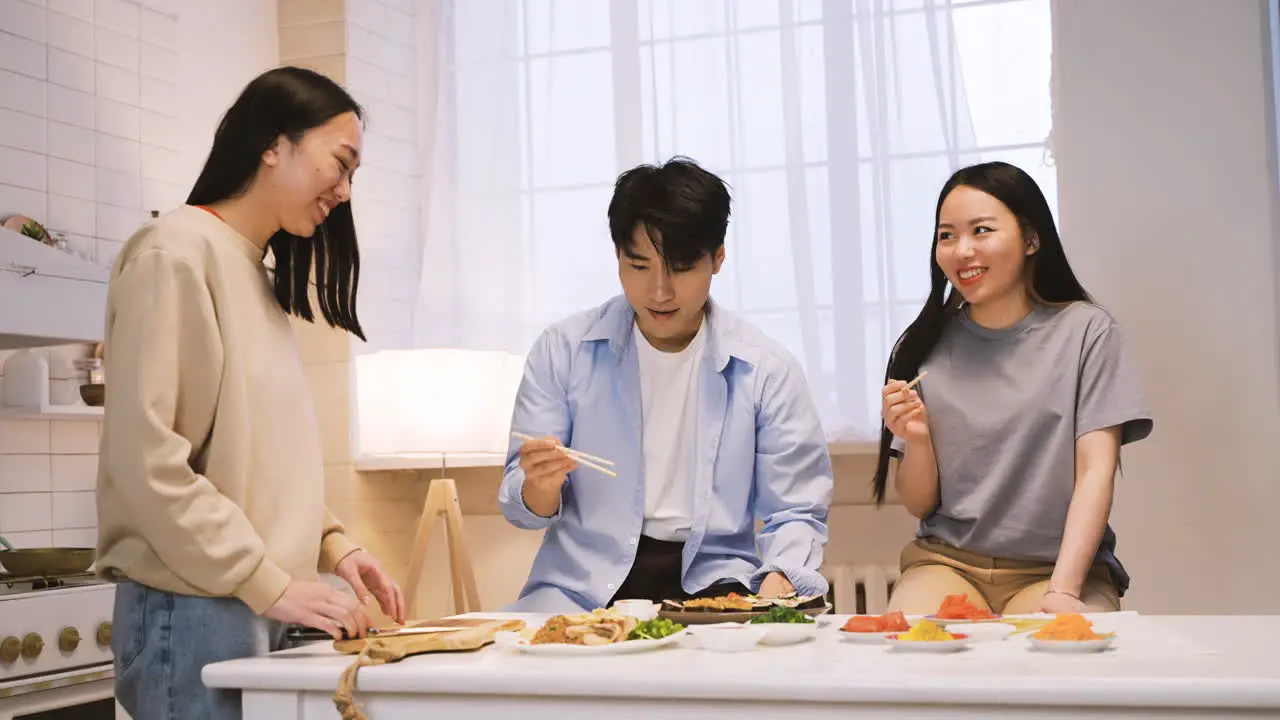 Tres Amigos Japoneses Sentados Alrededor Del Mostrador De La Cocina Cortando Y Comiendo Sushi 1