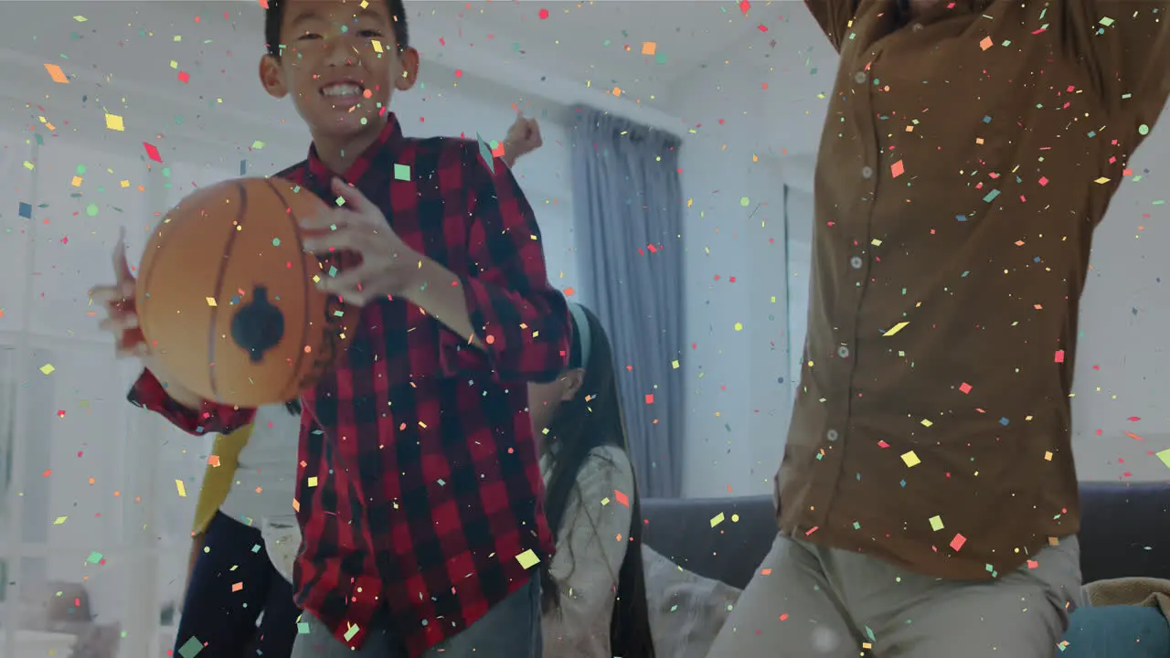 Composite video of confetti falling against asian family cheering while watching sports on tv