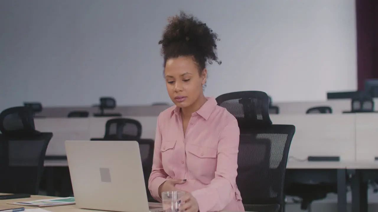 Pregnant Woman Using Laptop Computer And Drinking Water While Working In The Office