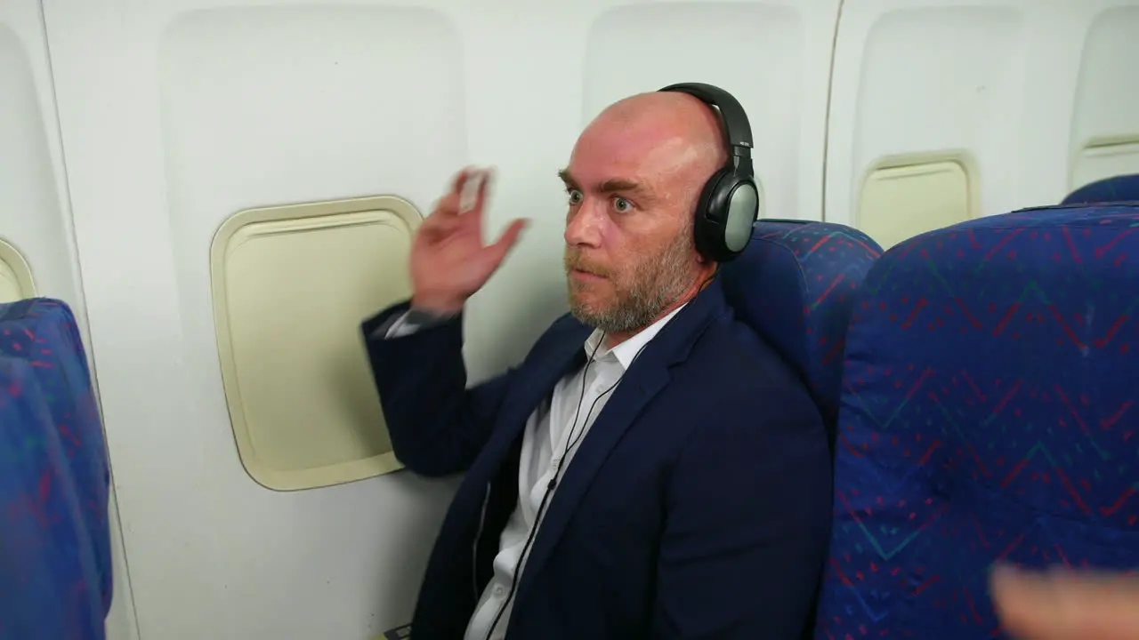 Funny loud man singing with headphones on a passenger airplane airliner told to be quiet by cabin crew