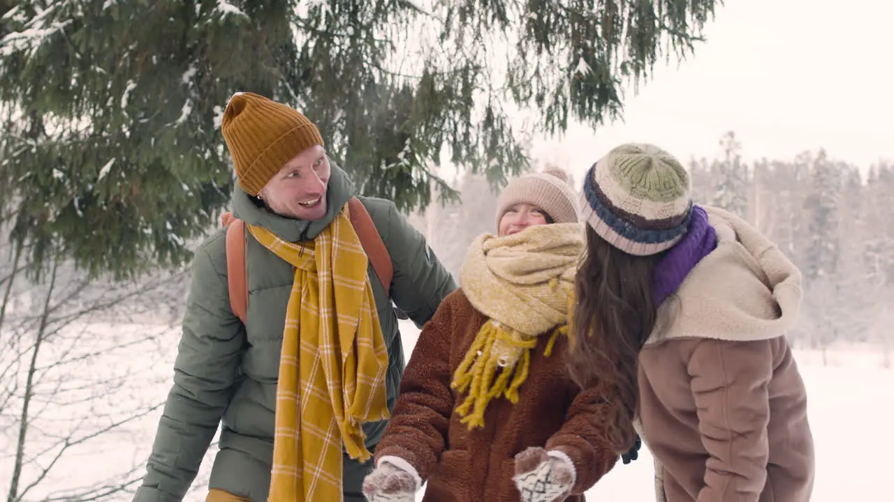 Parents And Daughter Dressed In Winter Clothes Throwing Snow In A Snowy Forest