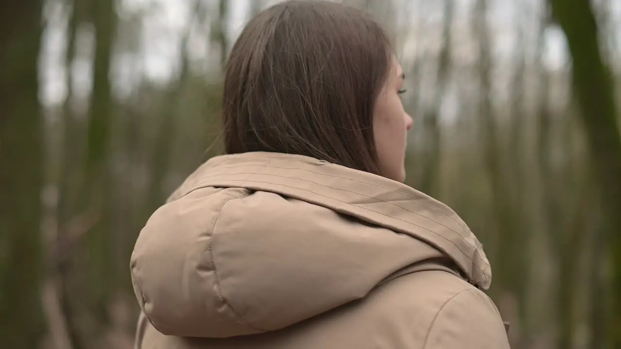 A Young Girl Walks Through The Forest And Removes The Hood Of Her Coat