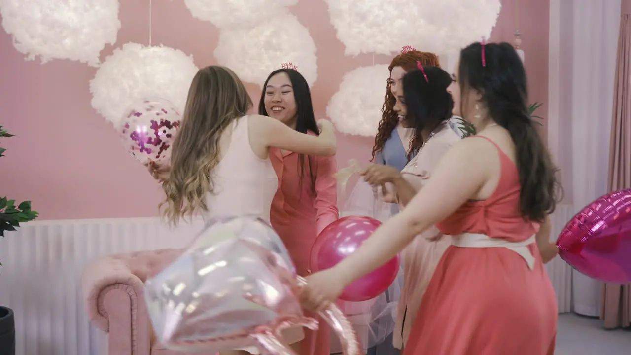 Side View Of Four Women With Headdresses Jumping And Holding Ballons