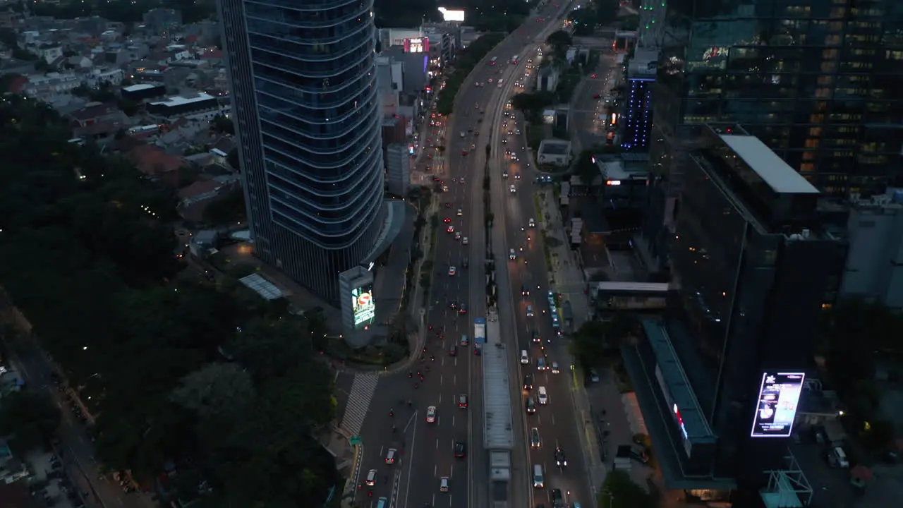 Aerial tilting shot following traffic on a multi lane highway into the modern city center with skyscrapers in Jakarta