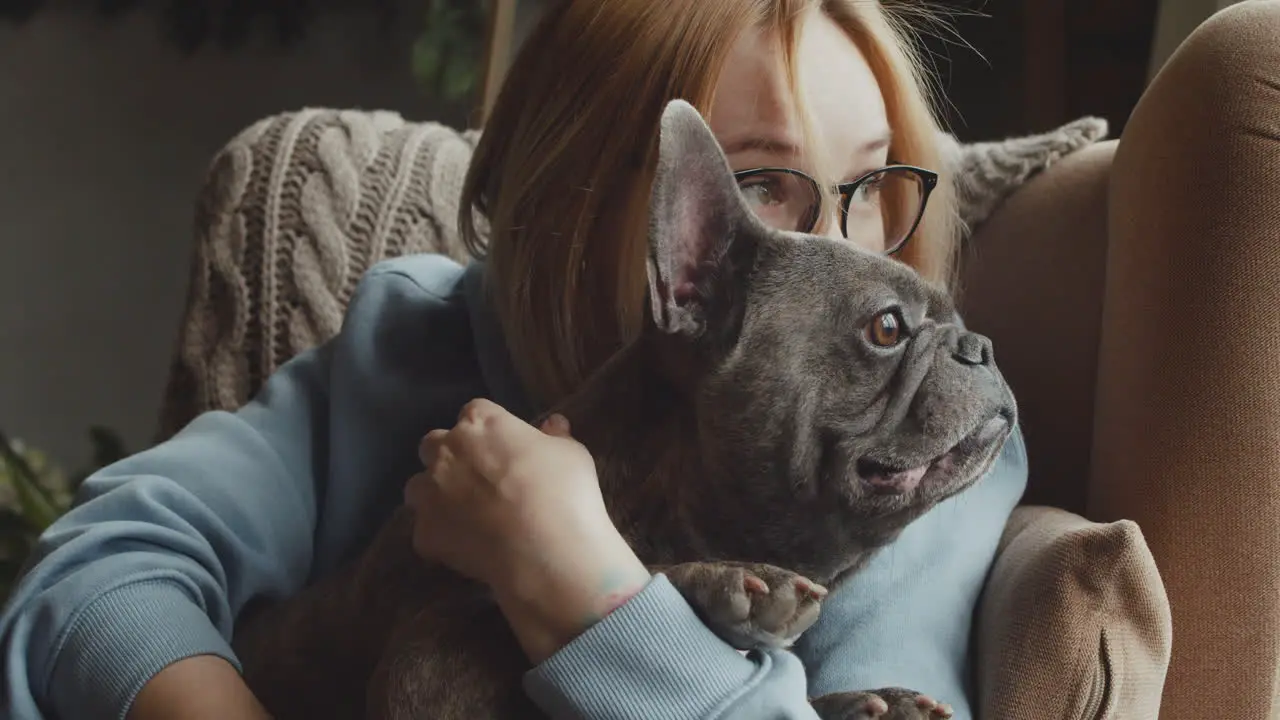 Close Up View Of Red Haired Woman Caresses Her Bulldog Dog While They Are Sitting On The Sofa In The Living Room At Home 4