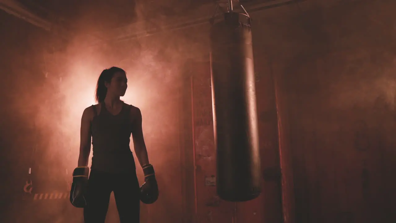 Female Boxer Rests Next To The Punching Bag