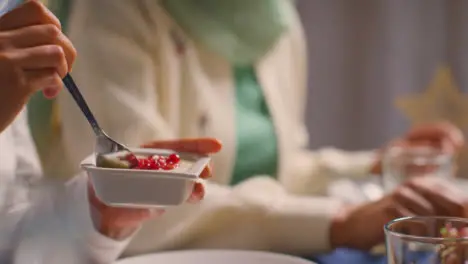 Close Up Of Muslim Muslim Family Sitting Around Table At Home Eating Meal Together