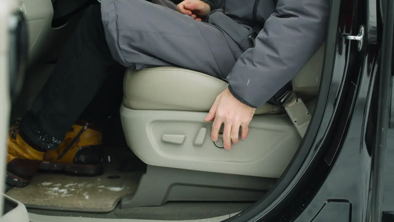 Man Sitting On His Car Adjusting Driving Seat And Steering Wheel During A Snowy Winter Day