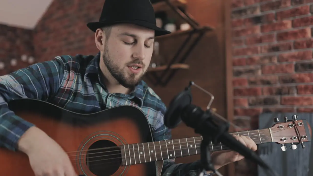 Portrait Of Young Male Musician Playing Guitar And Singing Recording A Song At Home