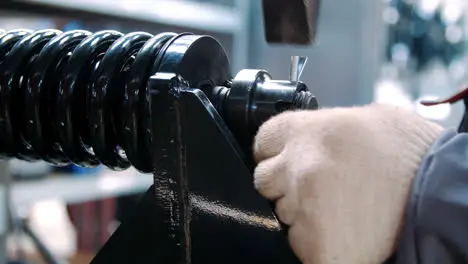 Worker fixing black spring during assembly shock absorber at industrial plant