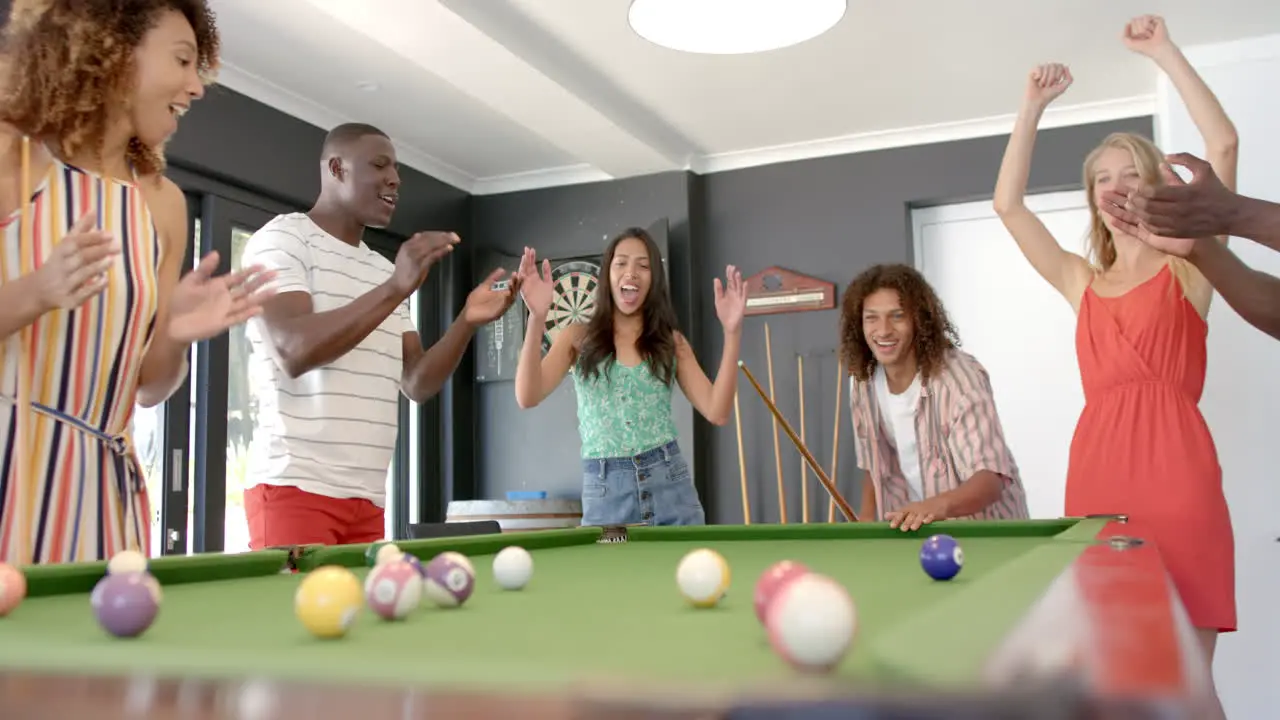 Diverse friends enjoy a game of pool at home