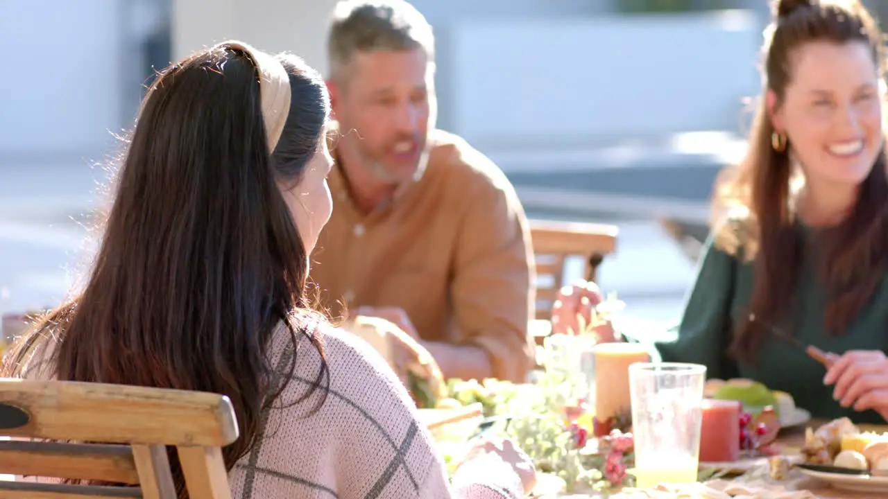 Happy diverse male and female friends eating thanksgiving celebration meal in sunny garden