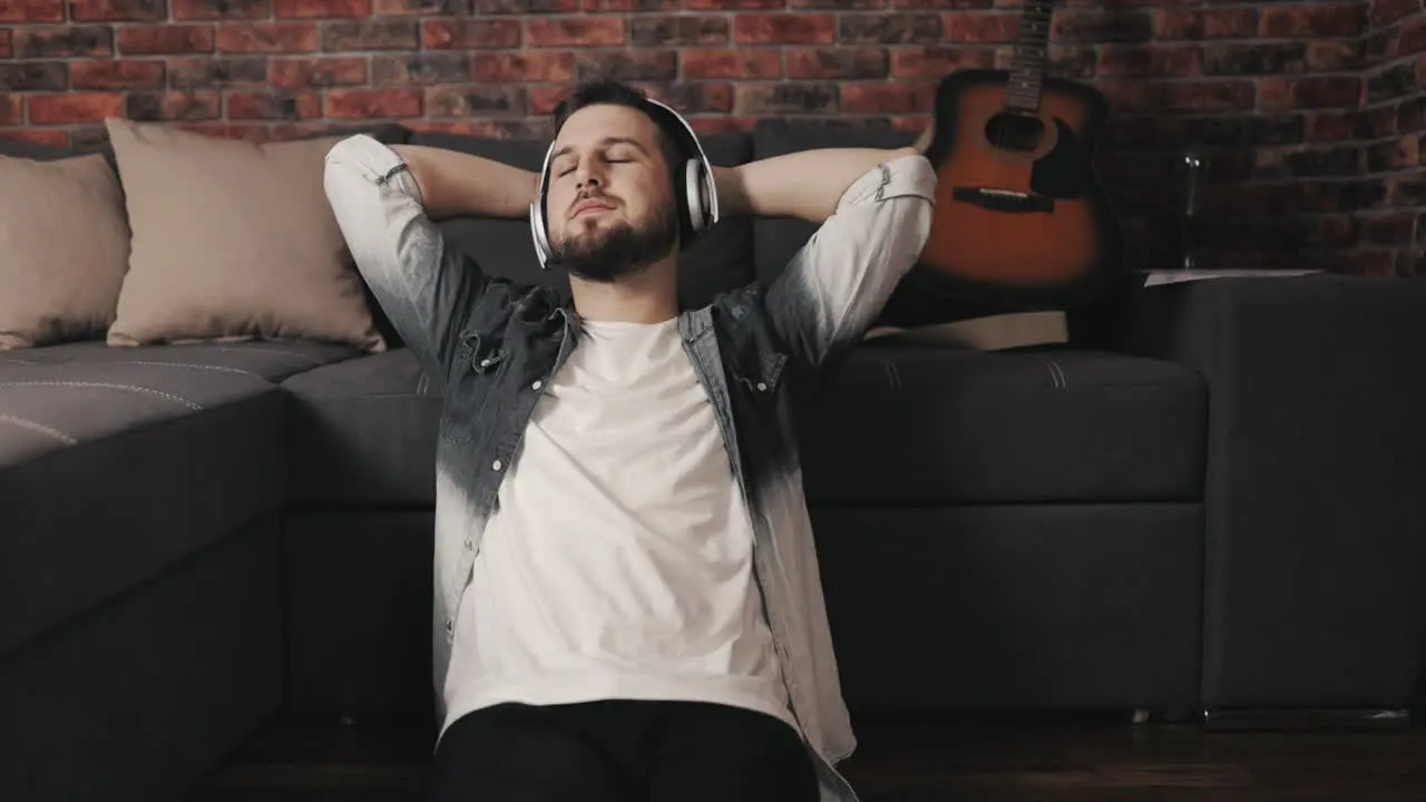 Young Musician Man Listening To Music With Wireless Headphones And Singing At Home