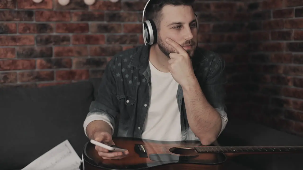 Young Musician Man Listening To Music With Smartphone And Wireless Headphones At Home