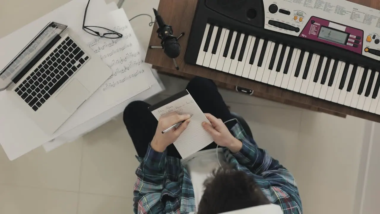 Young Male Musician Creating Music And Taking Notes At Home