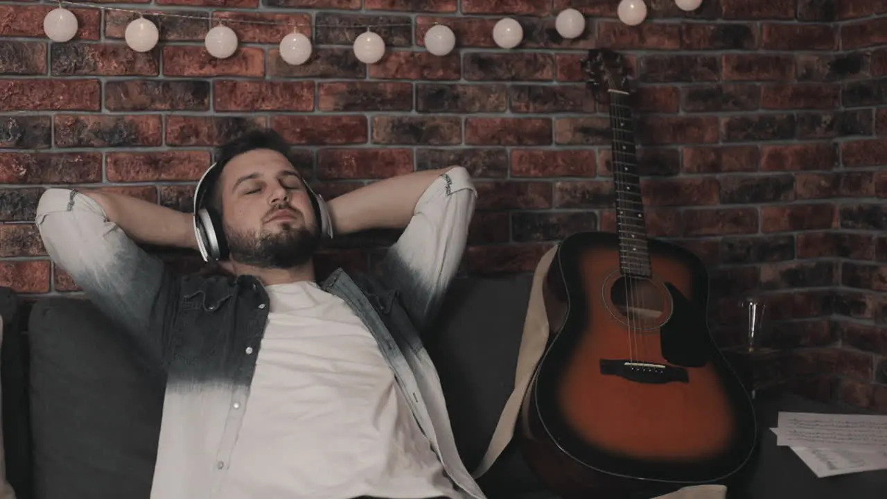 Young Musician Man Listening To Music With Wireless Headphones At Home