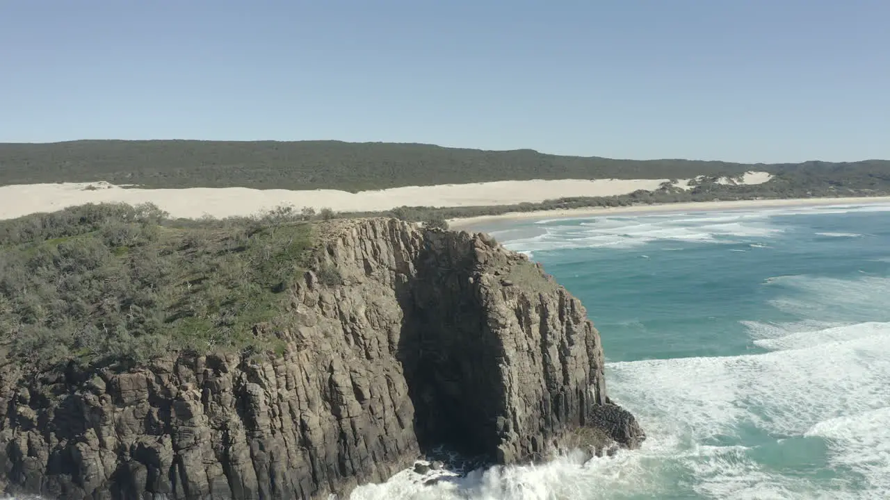 4k drone shot of a mountain cliff on a clear sunny day on the coast of Fraser Island Australia