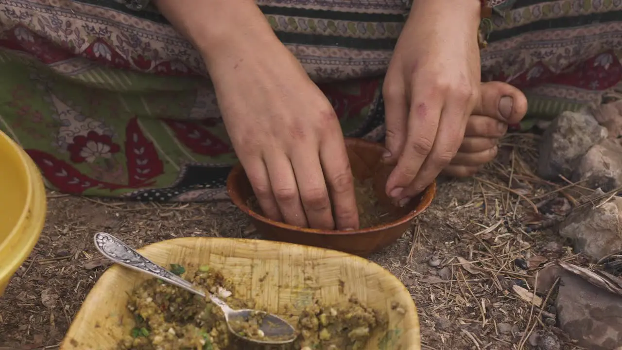 Indigenous woman preparing food with her hands while sitting on the ground