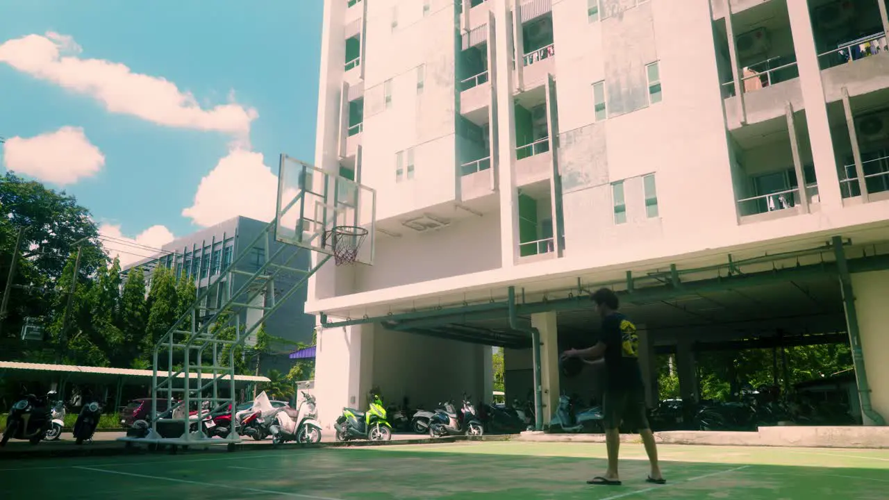 4K Cinematic sport footage of a man playing basketball alone outside on a sunny day