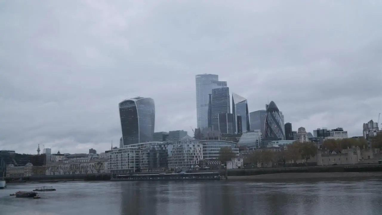 Central London skyscrapers on a cloudy rain day reflected in the Thames river