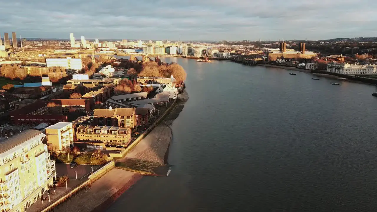 An aerial drone shot over the Thames river in London during sunset while waves are reaching to banks