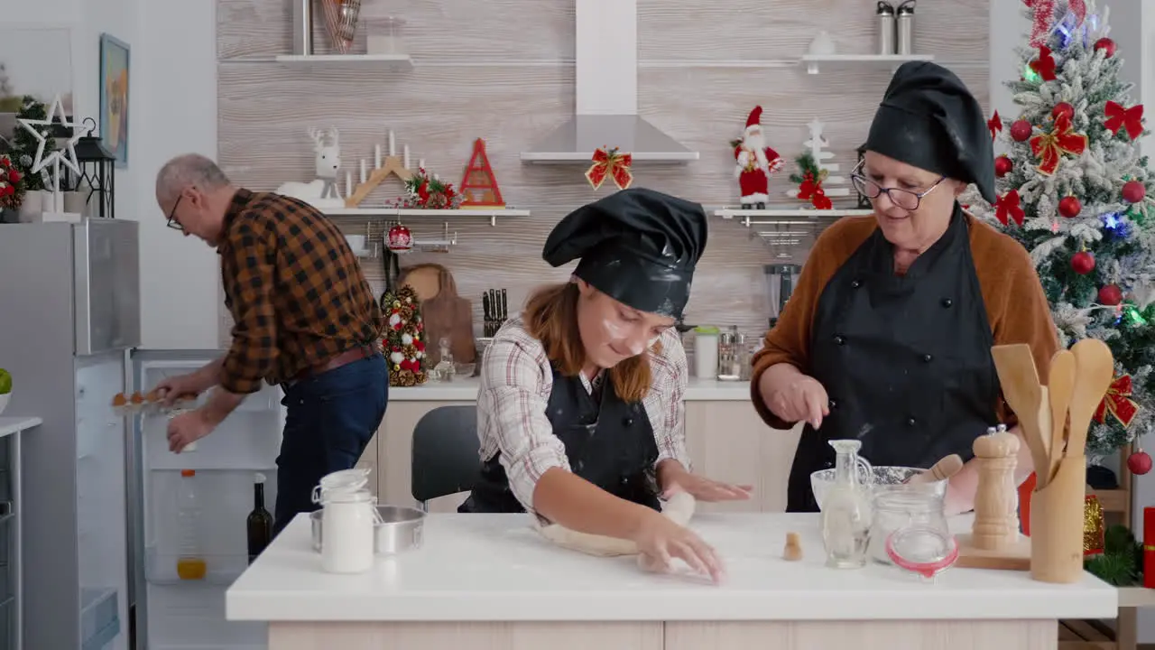 Grandparents helping granddaugher preparing traditional homemade dough