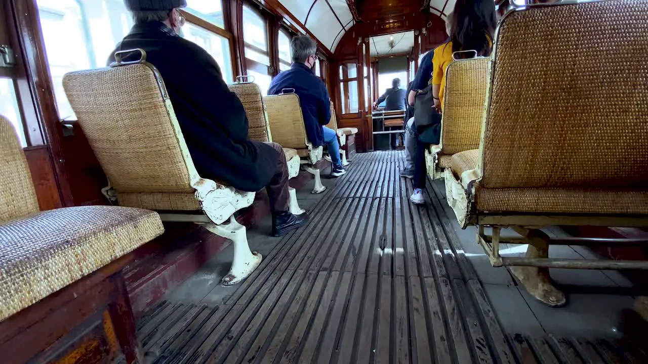 Wooden old tram Interior with people sitting on chairs during traveling tour in Porto city back view