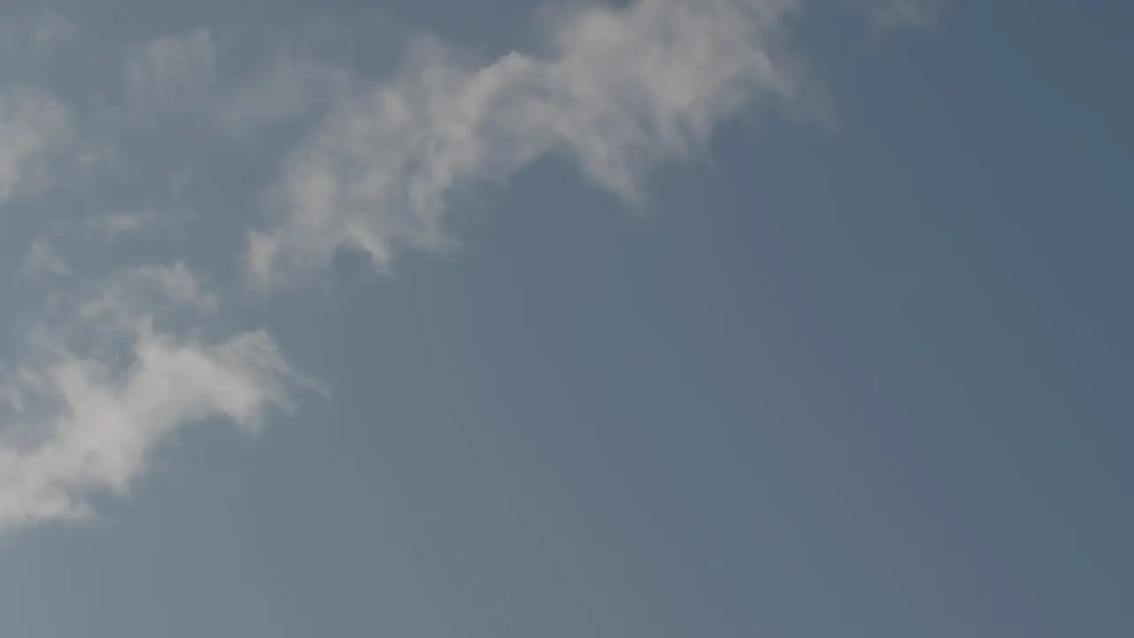 Slow motion wide shot of a sweat covered basketball as it arcs through a sky with clouds