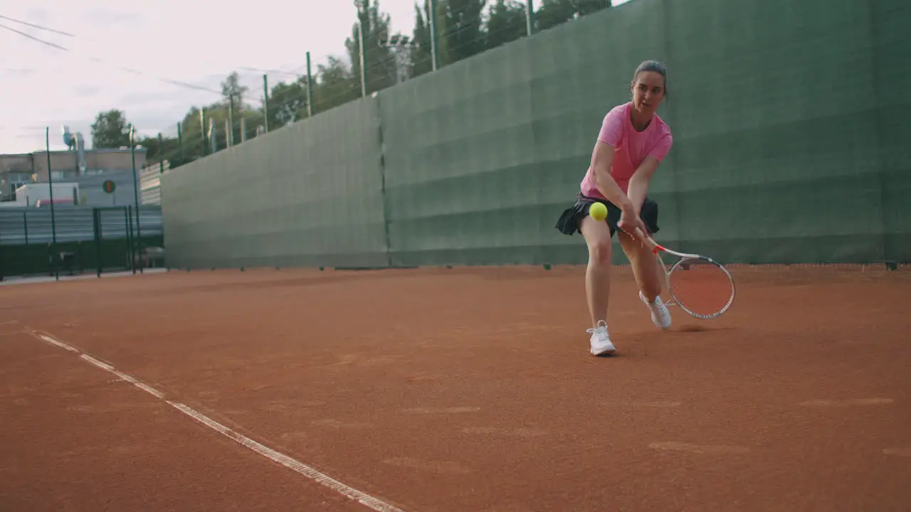 Young Caucasian woman playing tennis on a court returning a ball in slow motion