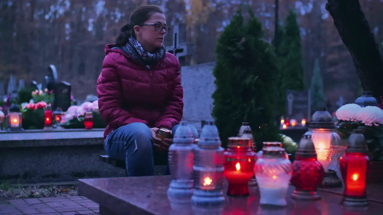 Woman sitting at a grave of her deceased ones in the evening